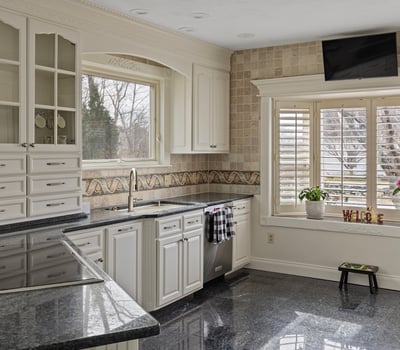 Modern kitchen featuring sleek granite countertops, abundant cabinetry, and a bright window with outdoor views.