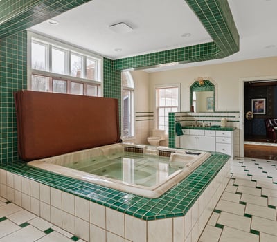 Spacious bathroom featuring a sunken tub, vibrant green tiles, and ample natural light throughout.