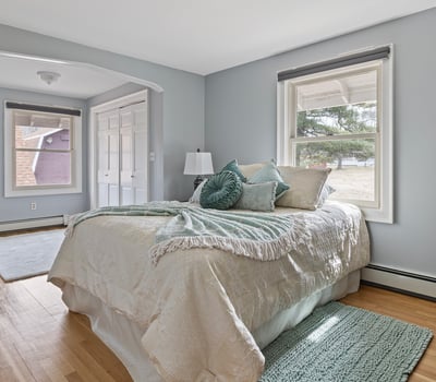 Bright bedroom featuring large windows, natural light, and ample closet space, perfect for relaxation and comfort.