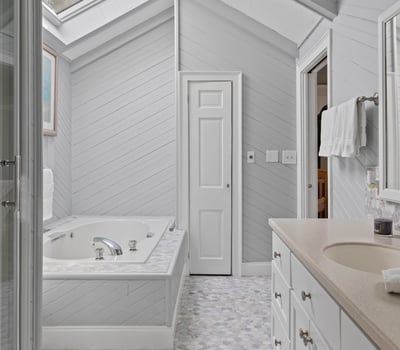Bright and airy bathroom featuring a skylight, spacious jacuzzi, and modern fixtures for a refreshing retreat.