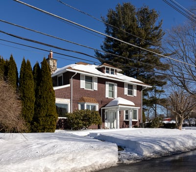 Spacious two-story home surrounded by trees, featuring ample outdoor space and winter scenery.