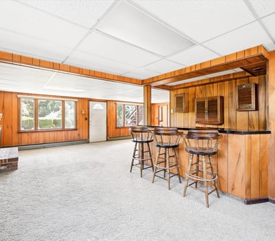 Spacious basement with built-in bar, large windows, and versatile layout perfect for entertaining or relaxation.
