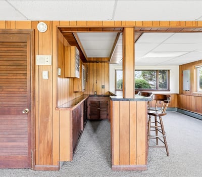 Spacious bonus room featuring natural light, wood paneling, and a convenient wet bar for entertaining.