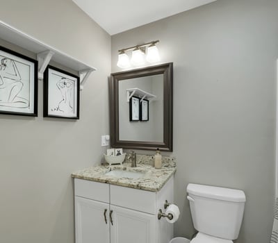Modern bathroom featuring a granite countertop, sleek fixtures, and contemporary artwork for added character.