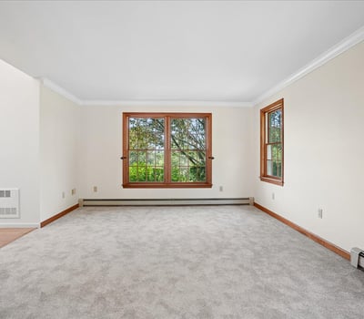 Bright and airy living space featuring large windows and plush carpeting, ideal for personalization and comfort.