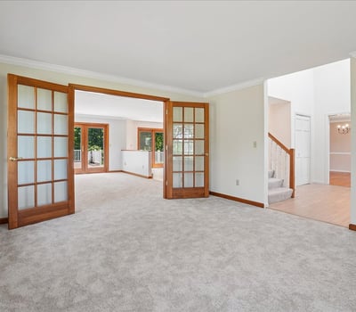 Spacious living area with abundant natural light, featuring dual French doors for flexible entertaining options.
