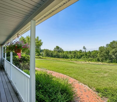 Enjoy expansive views and outdoor living from this welcoming wraparound porch, perfect for relaxation or entertaining.