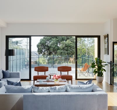 Modern living room featuring large windows, stylish furniture, and seamless access to an outdoor terrace.