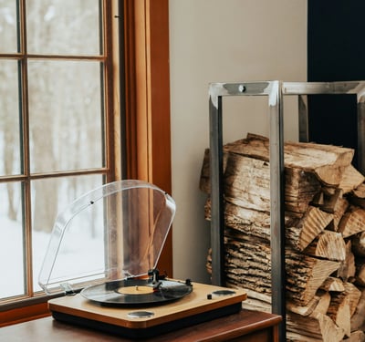 Cozy space featuring a vintage turntable beside a neatly stacked pile of firewood, perfect for relaxation.