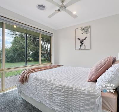 Bright and airy bedroom with large windows offering stunning views of the lush backyard.