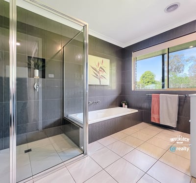 Modern bathroom featuring sleek tiles, a spacious shower, and large windows for natural light.