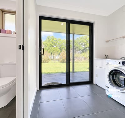 Bright laundry room featuring a washing machine, ample storage, and direct access to the outdoor space.