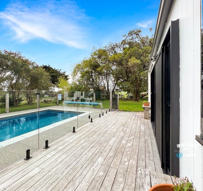 Discover a modern retreat featuring a spacious deck and inviting pool surrounded by lush greenery.