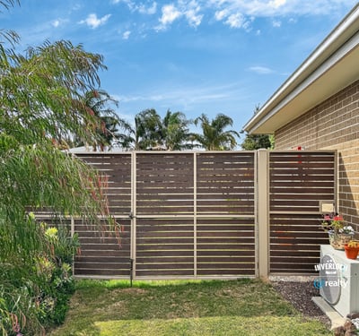 This property features a private outdoor space bordered by modern fencing and vibrant landscaping.