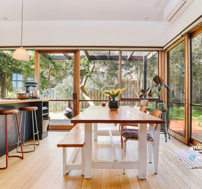 Bright and inviting kitchen and dining area seamlessly connect to a lush outdoor space, perfect for gatherings.
