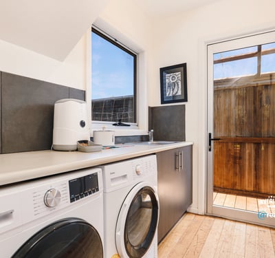 Bright laundry room featuring modern appliances and direct access to a private outdoor space.