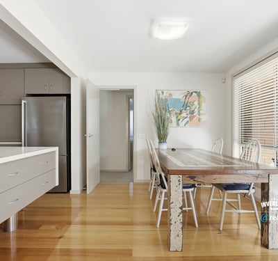 Bright and airy dining space featuring a rustic wooden table, modern kitchen amenities, and abundant natural light.