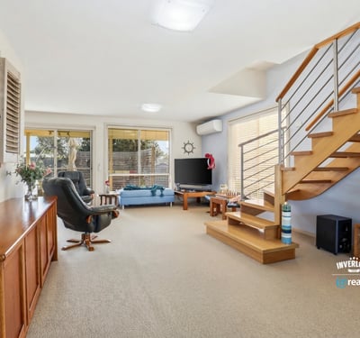 Bright and spacious living area with modern furnishings, featuring a staircase and natural light throughout.