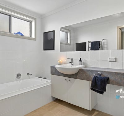 Modern bathroom featuring a spacious tub, sleek countertop, and ample natural light from large windows.