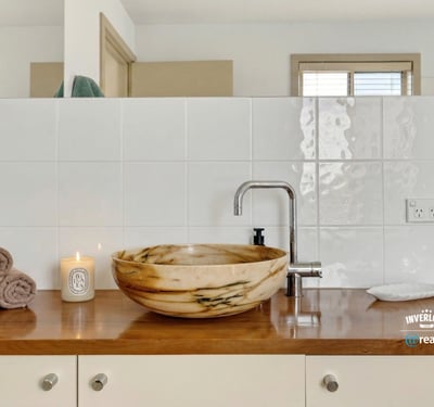 Discover a beautifully designed bathroom featuring a unique stone sink and warm, inviting accents.