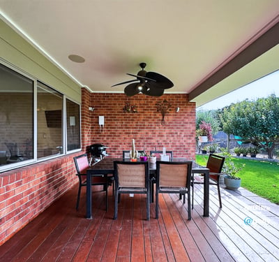 Experience outdoor dining on this spacious covered patio, featuring ample seating and picturesque landscaping.