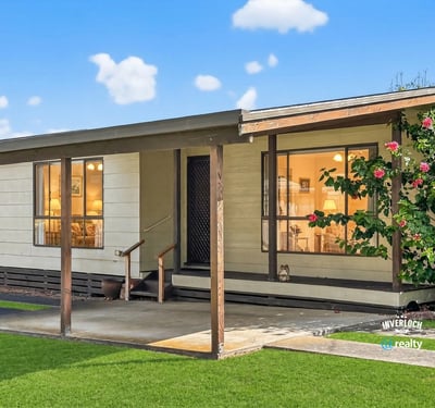 This inviting home features a spacious front porch and lush landscaping, perfect for outdoor relaxation.