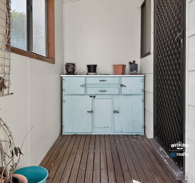 Bright and inviting enclosed porch featuring a rustic blue cabinet, perfect for additional storage and decor.