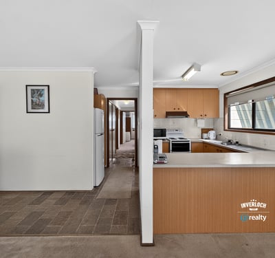 Spacious kitchen with ample cabinetry leads to a light-filled, open living space perfect for gatherings.