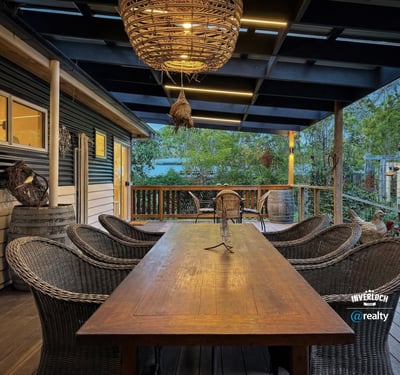 Relax on this spacious deck, featuring a generous dining area surrounded by lush greenery and rustic charm.