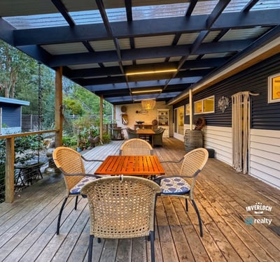 Spacious outdoor deck ideal for entertaining, featuring a cozy dining area and surrounding natural greenery.