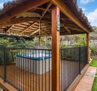 Relax in this private outdoor gazebo featuring a hot tub, surrounded by lush greenery.