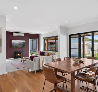 Bright and inviting open-plan living space featuring large windows and a cozy fireplace. Perfect for gatherings.