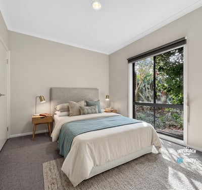 Bright bedroom featuring large windows, cozy furnishings, and a peaceful view of the outdoor greenery.