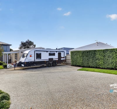 Spacious driveway perfectly accommodates an RV, surrounded by well-maintained landscaping for added privacy and convenience.
