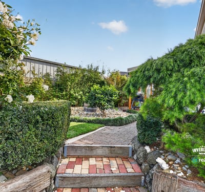 Discover a beautifully landscaped garden pathway surrounded by lush greenery and vibrant plant life.