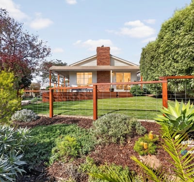 Discover a beautifully landscaped property featuring a spacious backyard with vibrant greenery and ample outdoor space.