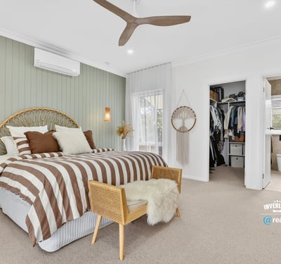Spacious bedroom featuring unique decor, natural light, and convenient access to an organized closet and bathroom.