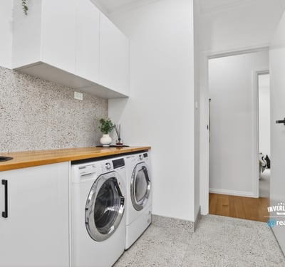 Bright laundry area featuring modern appliances, streamlined cabinetry, and a clean, functional design.