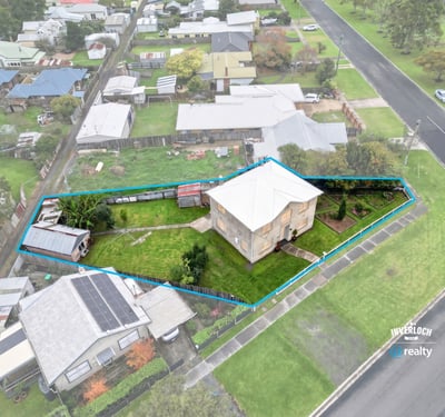 Spacious corner lot with potential for development, featuring a two-story home and ample outdoor space.