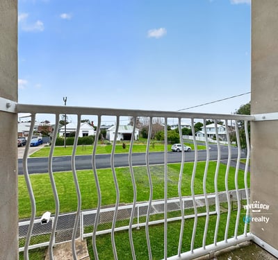Enjoy a peaceful balcony view overlooking a quiet street surrounded by greenery and residential homes.