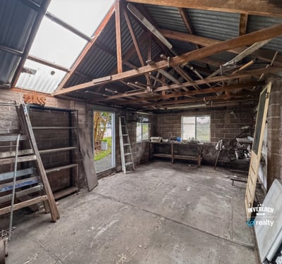 Spacious workshop with ample storage potential, featuring high ceilings and natural light for creative projects.