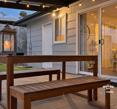 This inviting outdoor space features a wooden dining set and soft lighting, perfect for gatherings.