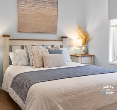 Bright and inviting bedroom features coastal decor, cozy bedding, and natural light streaming through the window.