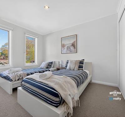 Bright and inviting bedroom with ample natural light, featuring twin beds and modern aesthetics.