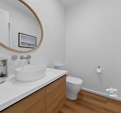 Bright and modern bathroom featuring a unique round mirror and sleek wood cabinetry for functional appeal.