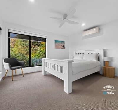 Bright bedroom with large windows showcasing natural light and leafy views, featuring modern finishes and comfort.