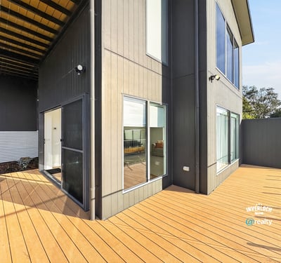 Modern home featuring a spacious outdoor deck and large windows, perfect for entertaining and natural light.