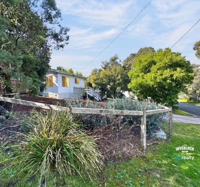 Quaint home nestled among lush greenery, featuring a spacious yard and a peaceful neighborhood setting.
