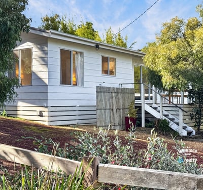 This inviting home features ample windows, a spacious outdoor area, and a welcoming front porch.