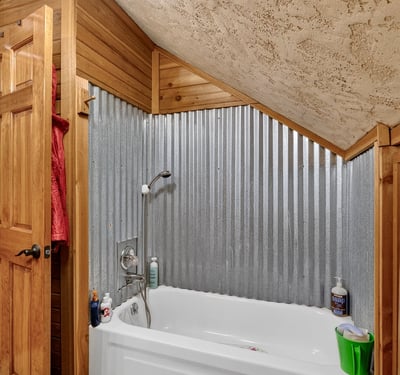 Cozy bathroom featuring a unique corrugated metal accent wall and a comfortable tub for relaxation.